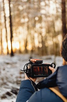 A photographer capturing a winter sunrise in a snowy forest with vibrant light.