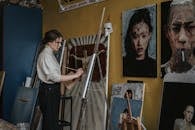 A Woman Painting in a Room Filled of Paintings