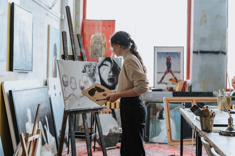 A Woman Painting Wine Glasses On A Canvas