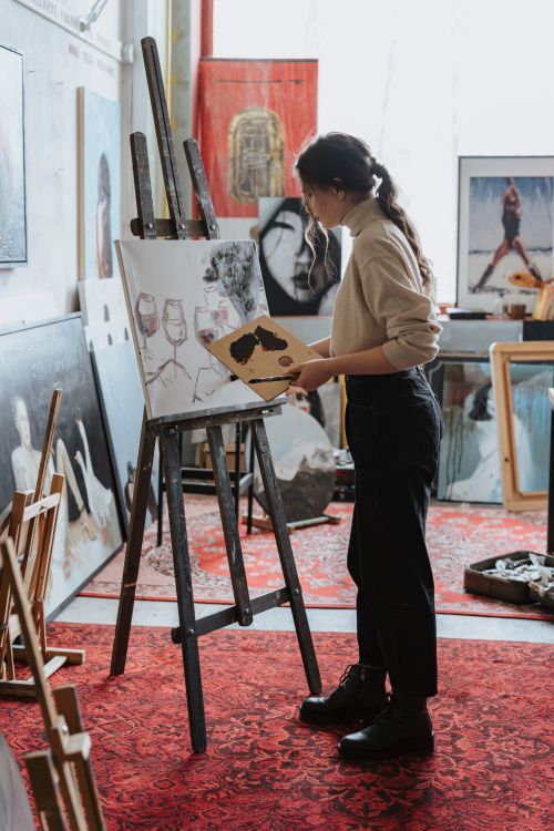Free Female artist painting on canvas in a vibrant studio space, showcasing creative process. Stock Photo