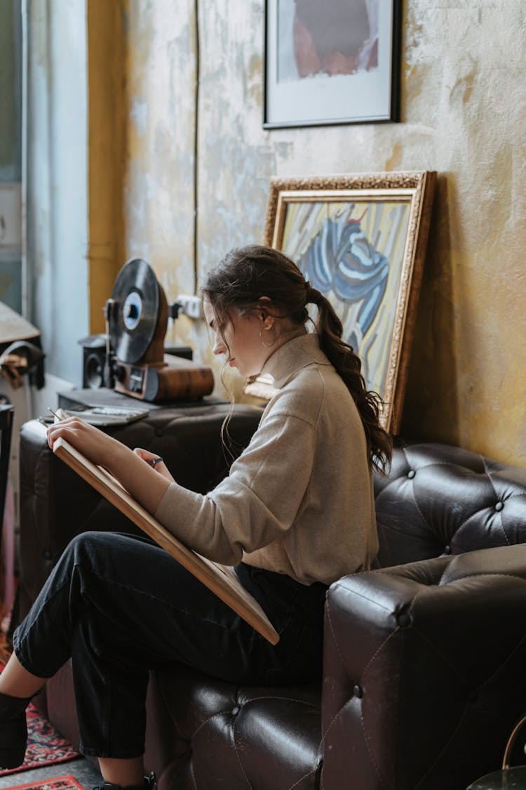 Close-Up Shot Of A Woman Drawing While Sitting On A Couch