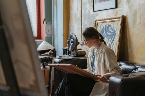 Free Young woman sketching in an artistic studio with vintage decor, seated on a sofa. Stock Photo