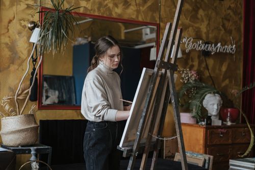 Free Artist painting on canvas in a stylish studio filled with decor and art objects. Stock Photo