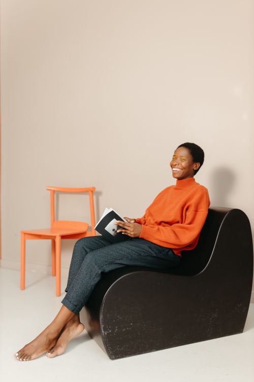 Free A woman in a cozy sweater reading indoors, embracing minimalism and relaxation. Stock Photo