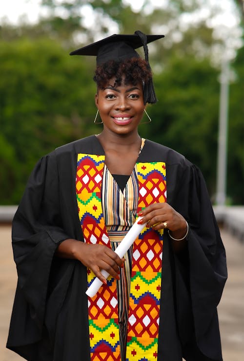 Happy Woman in Graduation Cap and Gown Holding a Diploma