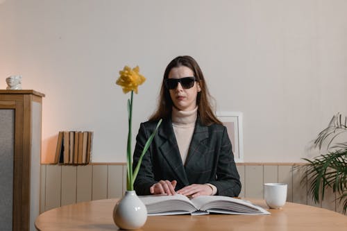 A Blind Woman wearing Sunglasses Reading a Braille Book
