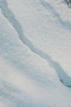 Close-up of a snow surface displaying a natural crack, perfect for winter-themed backgrounds.