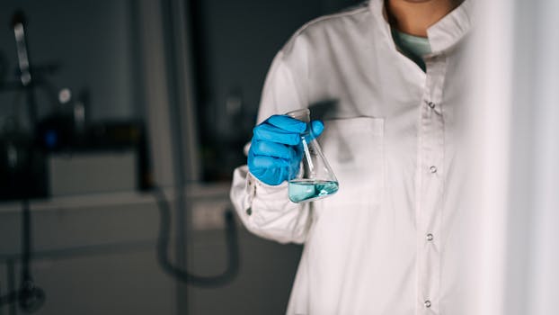 Scientist in white coat holding a flask with blue liquid in a laboratory, showcasing scientific research.