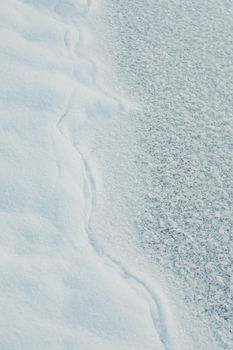 A close-up view of textured snow and ice patterns depicting cold winter conditions.