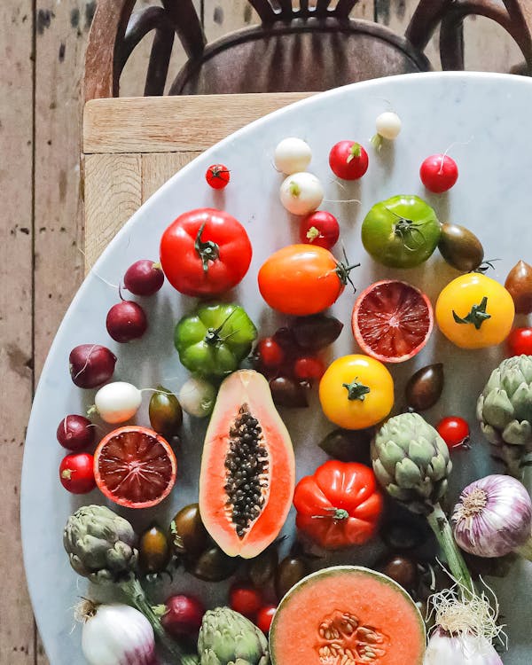 Free Top view of assorted exotic fruit with citrus and various vegetables of tomatoes and onions on round table Stock Photo