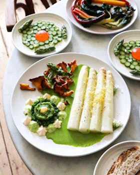 Delicious vegetarian dish with asparagus and assorted vegetables on white plates.