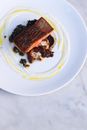 From above of appetizing fried fish fillet served on white plate with mushrooms and sauces on marble table in kitchen