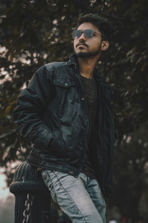 Free Young man with sunglasses and leather jacket posing outdoors on a moody day. Stock Photo