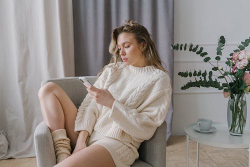 

A Woman Using Her Smartphone while Sitting