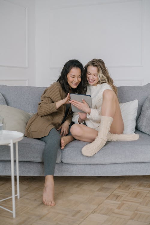 
Women Looking at a Digital Tablet while Sitting on Sofa