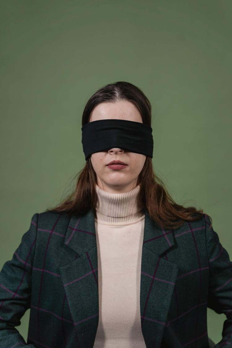 A Woman In Brown Turtle Neck Shirt With A Black Blindfold