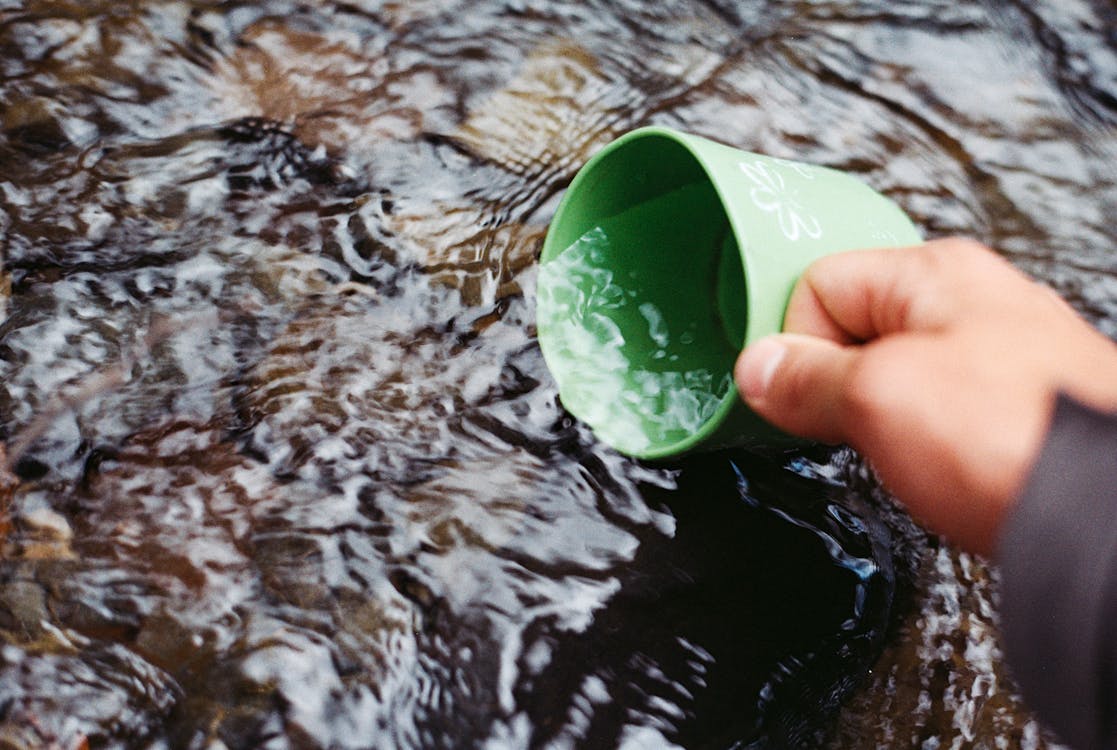 무료 그린 컵을 사용하여 물을 퍼내는 사람 스톡 사진