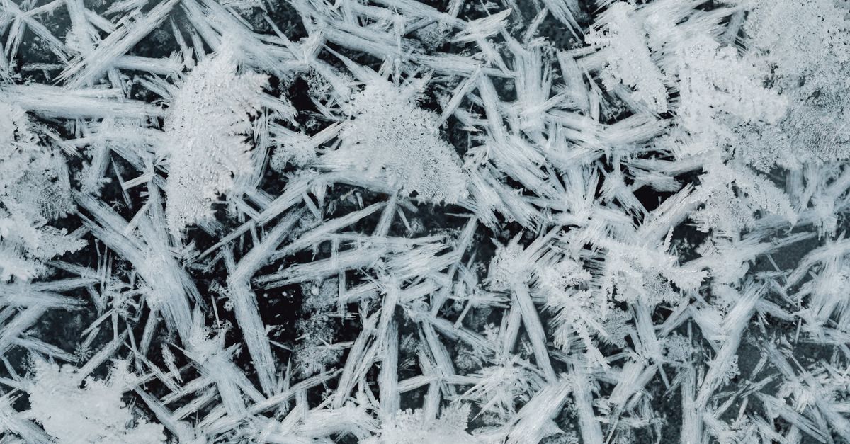 Captura detalhada de cristais de gelo formando padrões intrincados de flocos de neve.