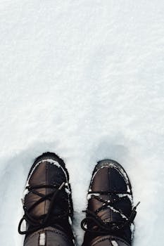Close-up of black boots stepping through fresh snow, capturing a winter moment.
