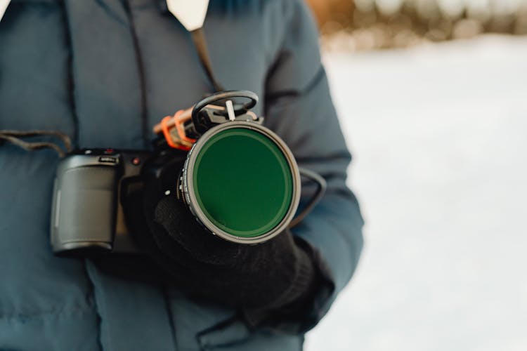 Close-up Of A Person Holding A Professional Camera With A Big Lens Outdoors In Winter 