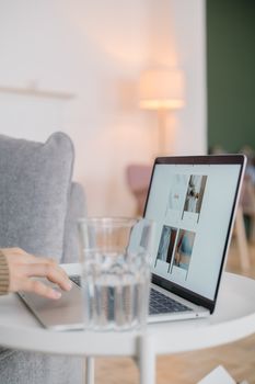 A serene home office setup featuring a laptop on a table with a glass of water and a cozy background.