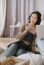 Woman in Brown and White Striped Long Sleeve Shirt and Blue Denim Jeans Sitting on Gray
