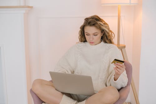 Free Woman in White Sweater Sitting on Chair Holding Silver Ipad Stock Photo