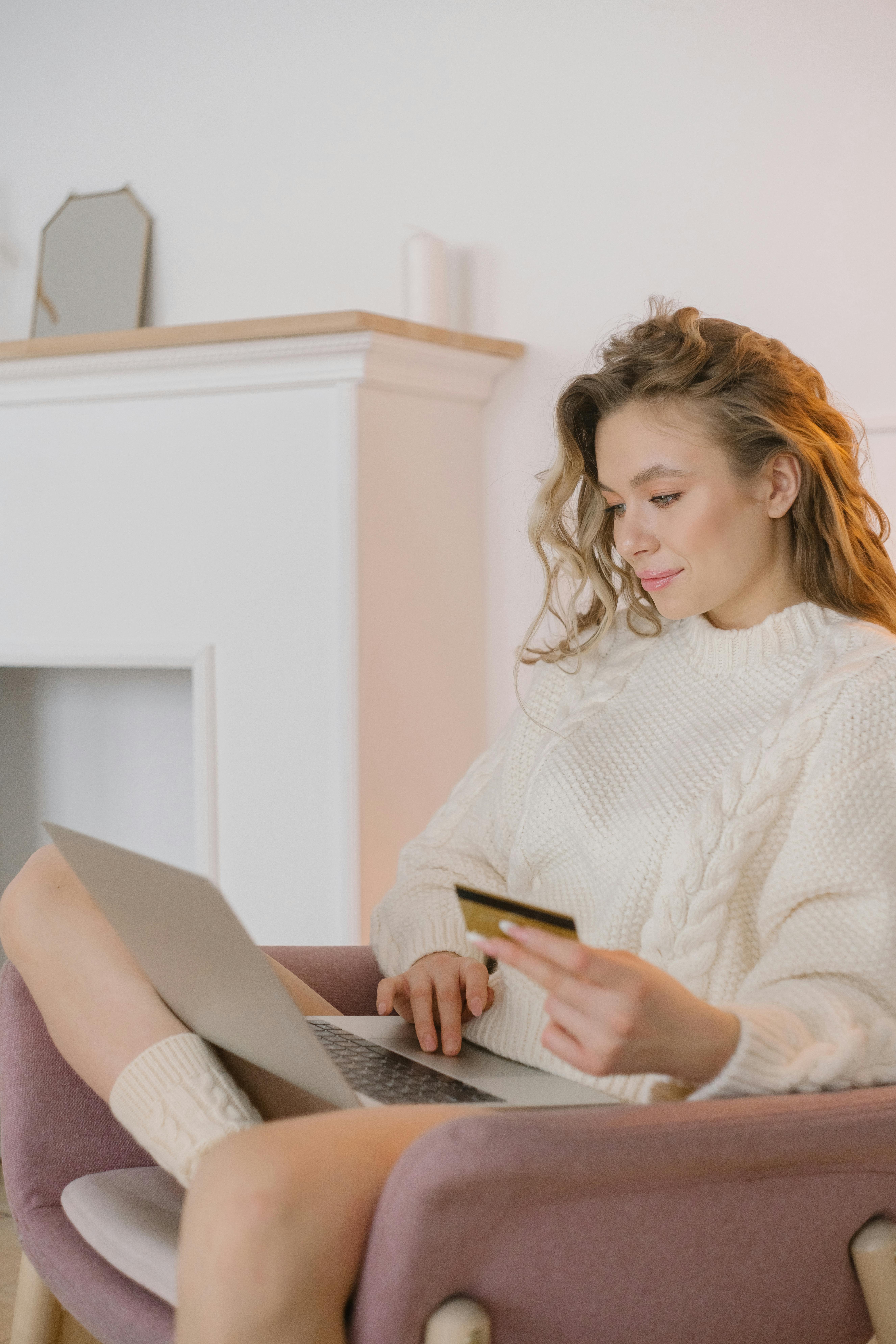 woman in white sweater doing online purchase with laptop and credit card