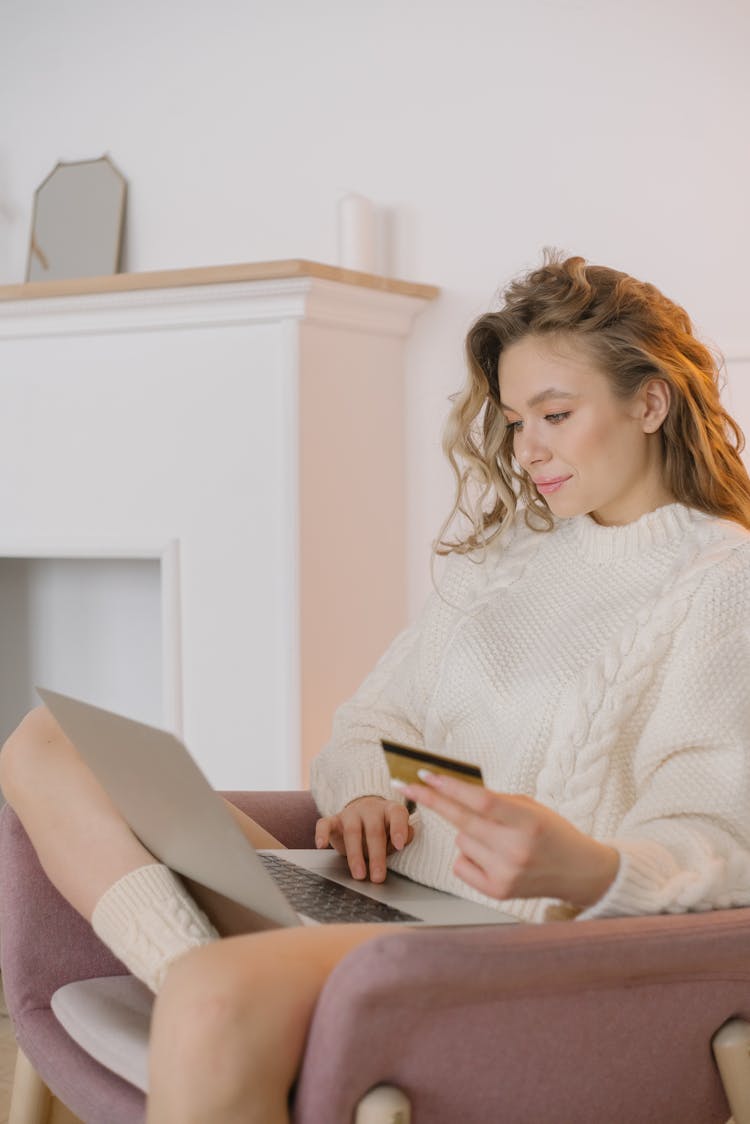 Woman In White Sweater Doing Online Purchase With Laptop And Credit Card