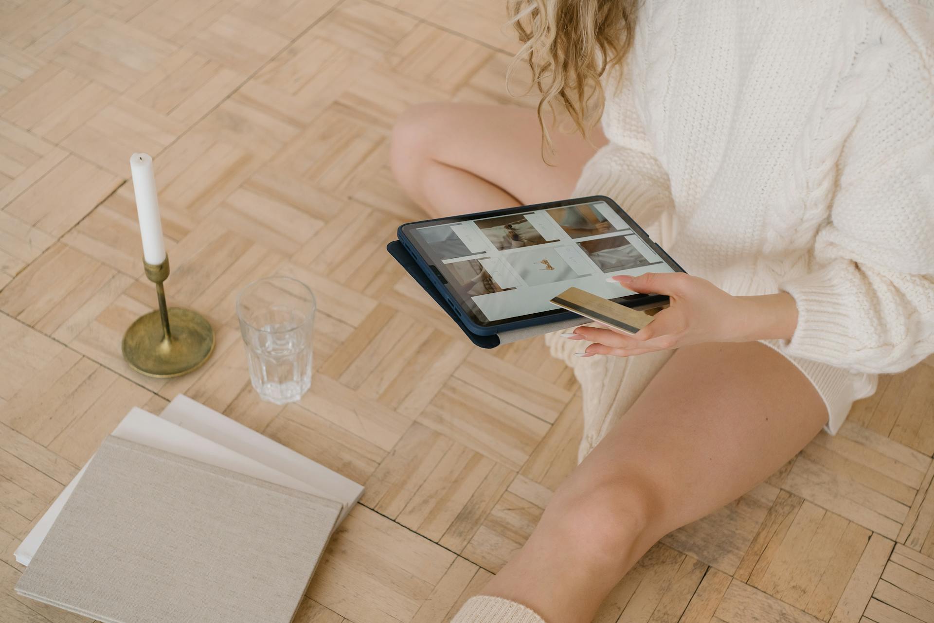 Woman using a tablet for online shopping while sitting indoors with a bank card.