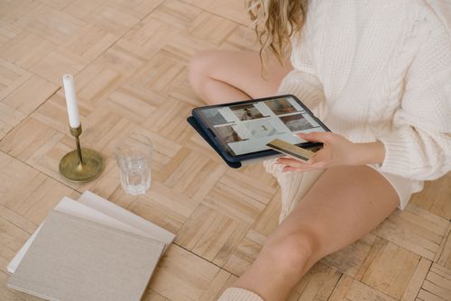 Free Woman using a tablet for online shopping while sitting indoors with a bank card. Stock Photo