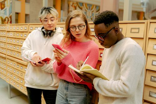 Free A group of students studying together with books and notes in a library setting. Stock Photo