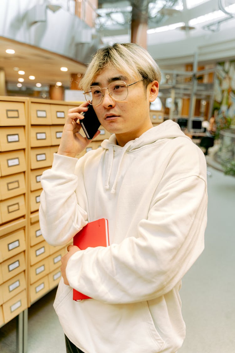 Portrait Of Man Talking On Smart Phone In Library