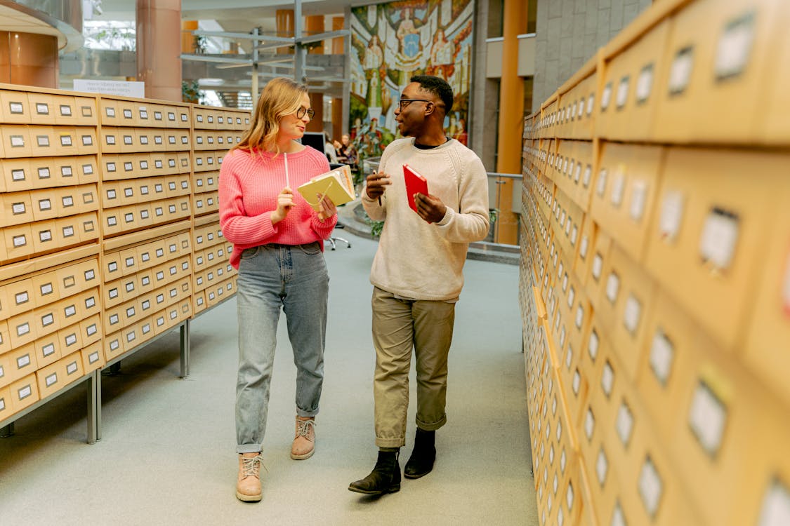 People in Library Catalogue Section Talking · Free Stock Photo