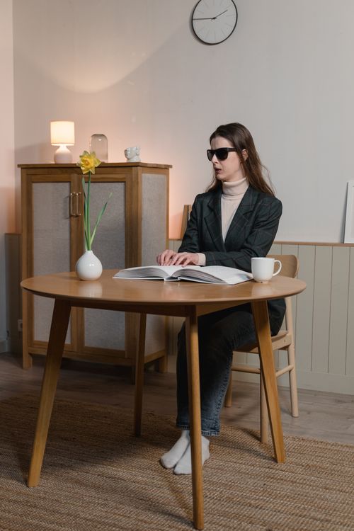 Free Blind woman reading braille book at a wooden table indoors, symbolizing independence Stock Photo