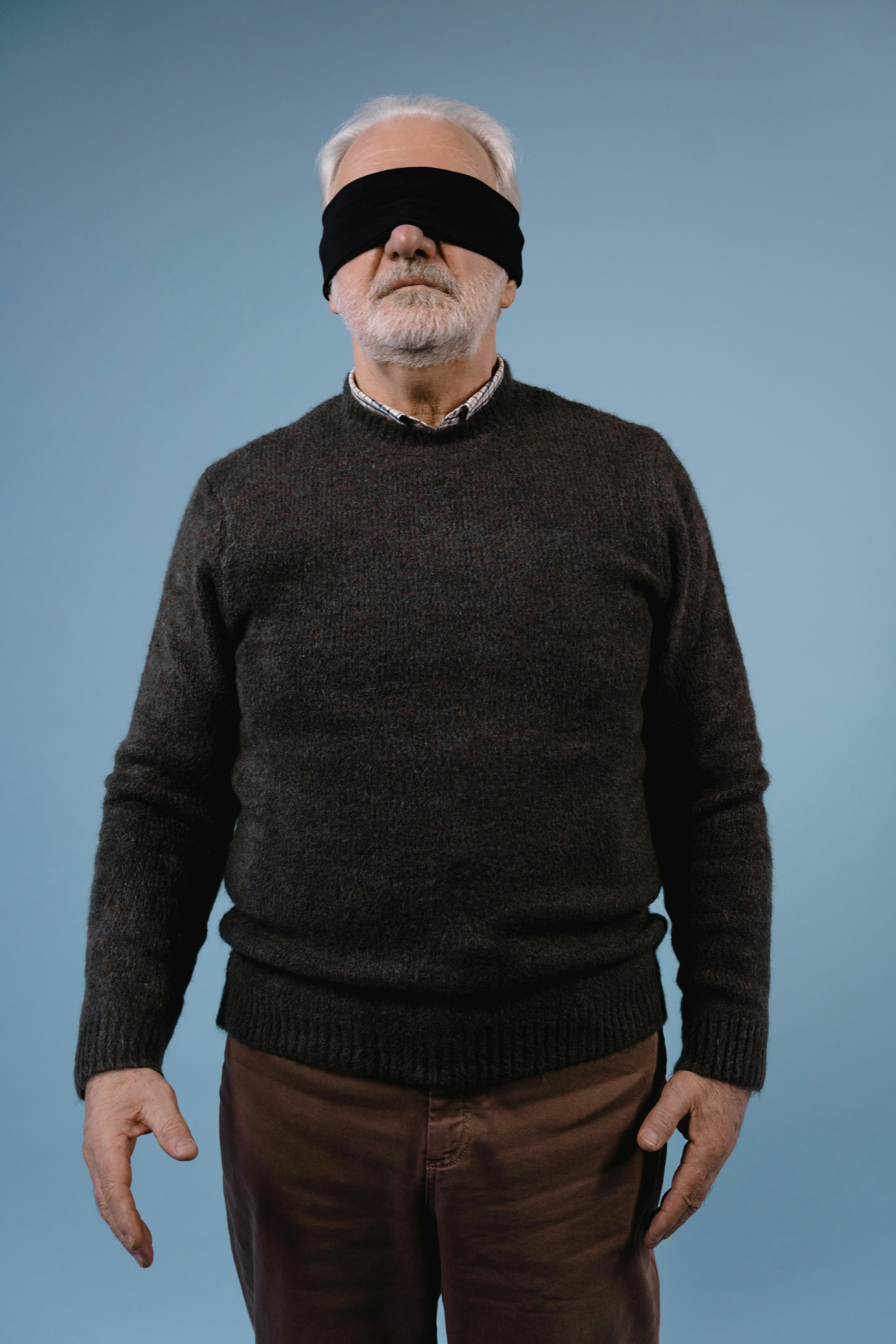 elderly man in black sweater with black fabric on covered eyes