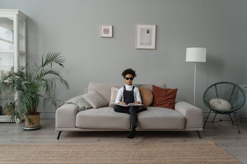 Girl Holding a Book While Sitting on Sofa