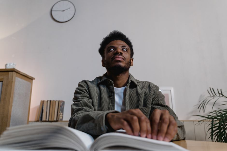 developing critical thinking skills - A blind man uses tactile senses to read a Braille book in a comfortable indoor setting.