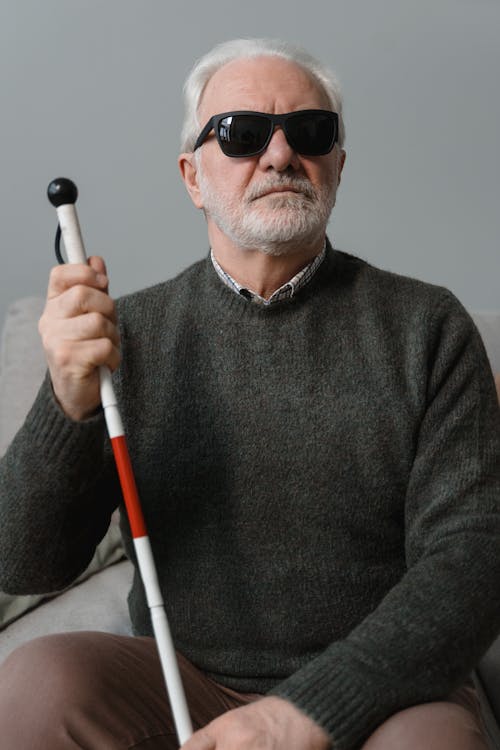 Man in Gray Sweater Holding White and Red Walking Stick