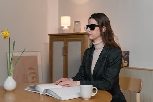 Woman in Black Blazer Sitting on Brown Wooden Chair using Braille
