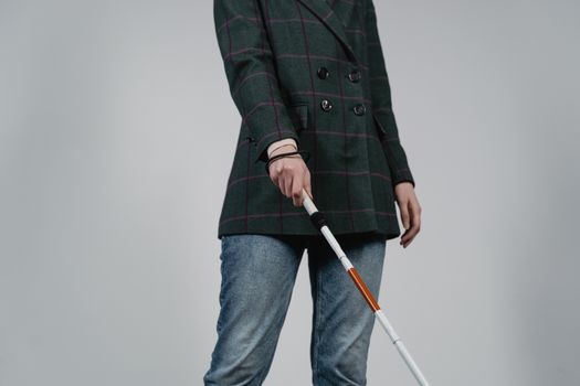 A person wearing casual clothes using a walking cane for assistance indoors.