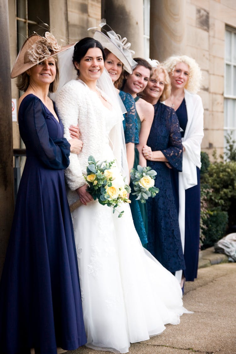 A Bride Holding A Bouquet Of Flowers With Friends And Family