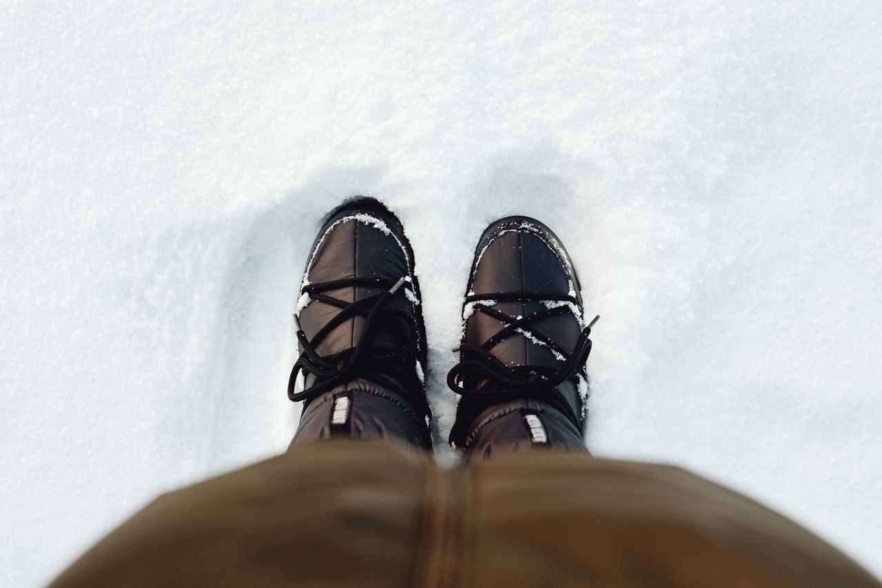 Black snow boots standing in deep snow, seen from above