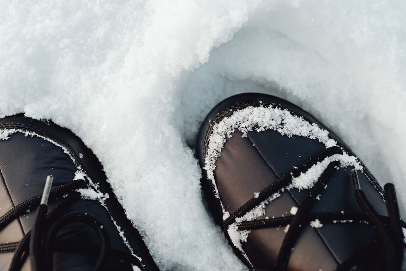 Black winter boots in fresh snow, close-up