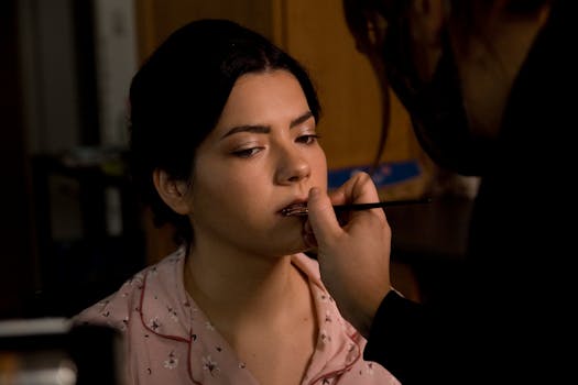 A makeup artist applies lipstick to a woman, showcasing beauty and professionalism.