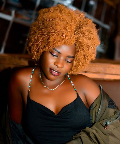 Free Vibrant close-up portrait of a woman with afro-textured hair in a cozy indoor environment. Stock Photo