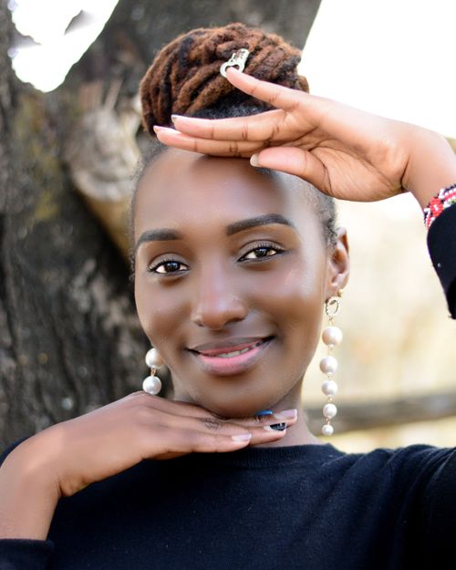 Free Portrait of a smiling woman posing outdoors with a unique hand gesture. Bright and vibrant mood. Stock Photo