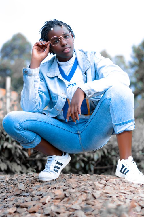 Free Young woman in denim jacket and jeans posing outdoors with eyeglasses. Stock Photo