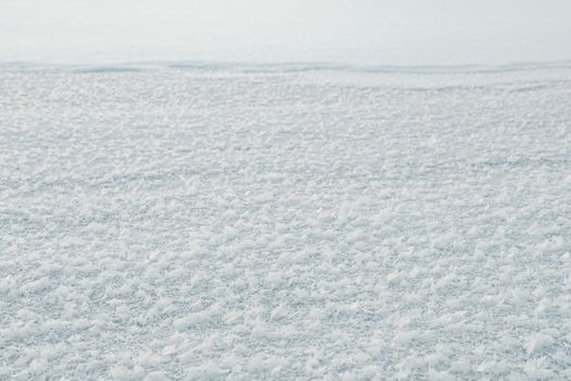 A detailed close-up shot of a frozen snow surface showcasing frost patterns in winter.