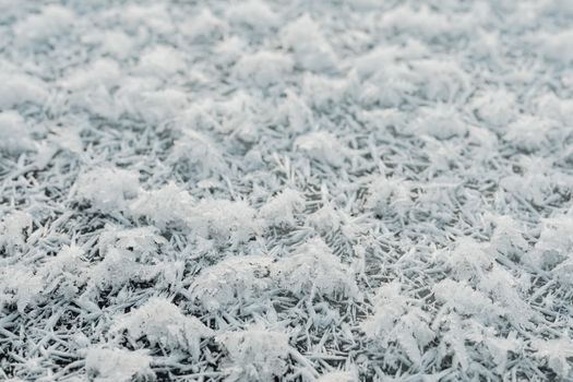 Detailed close-up of frosty ground covered in ice crystals in winter.